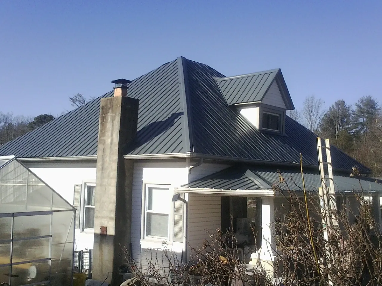 Dark blue standing seam metal roof on a white farmhouse with dormer — Slate & Tile Roof Repair by Roofing Brothers in Marseilles