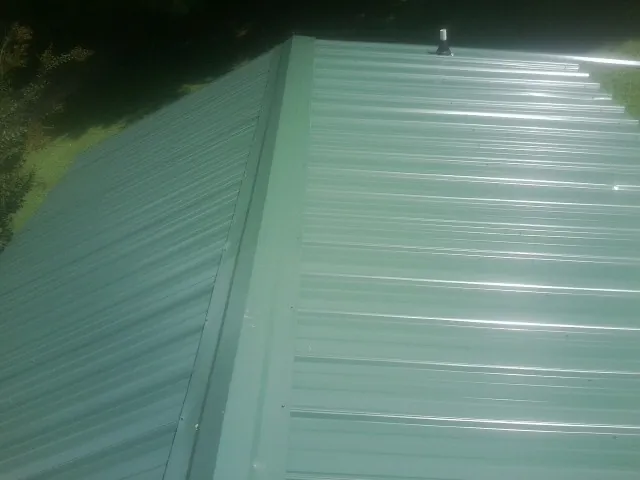 New green metal panels meeting at the ridge of a roof — Flat Roof Repair work by our crew in Marseilles