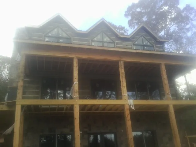Dormers and porch framing on a large log home under construction — Roof Coating work by our crew in Marseilles