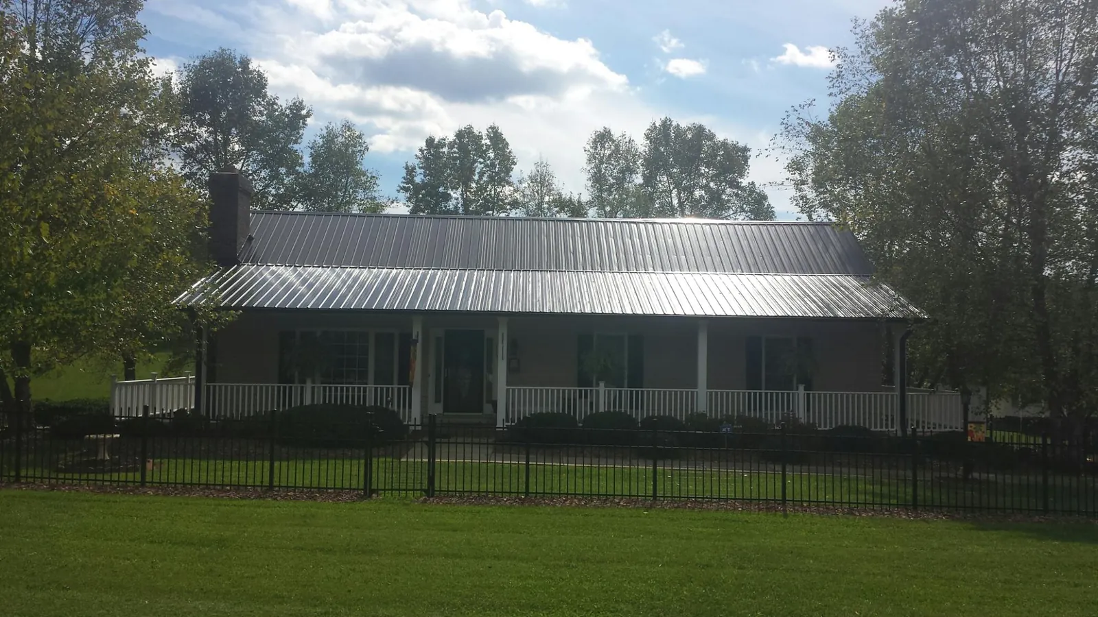 Gray metal roof on a brick ranch with a full width front porch — Gutter Guard Installation work by our crew in Marseilles
