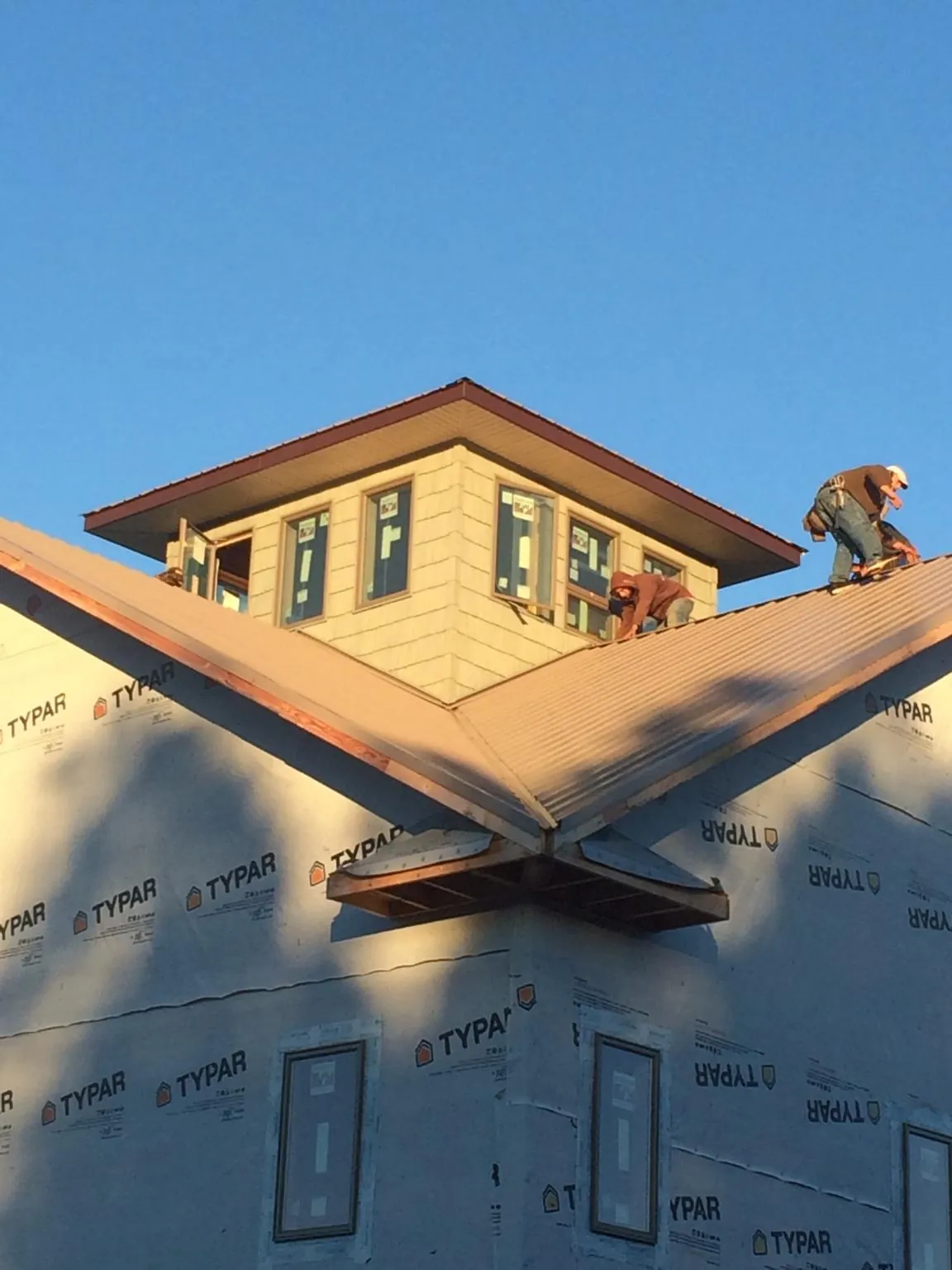 Roofers working around a rooftop cupola on a new metal roof at sunset — Roof Waterproofing in Marseilles by Roofing Brothers